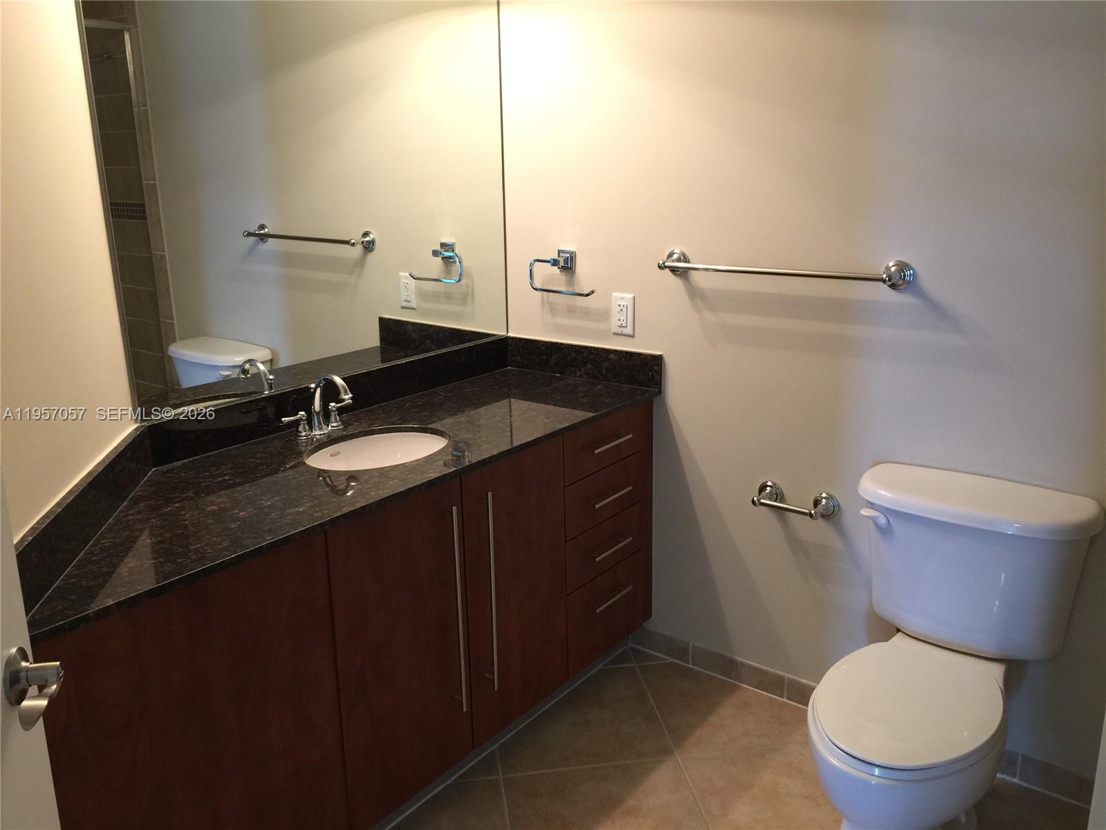7350 Southwest 89th Street, Unit 1611S Miami, FL 33156 - Photo 10 of 16 a bathroom with a granite countertop toilet sink and mirror