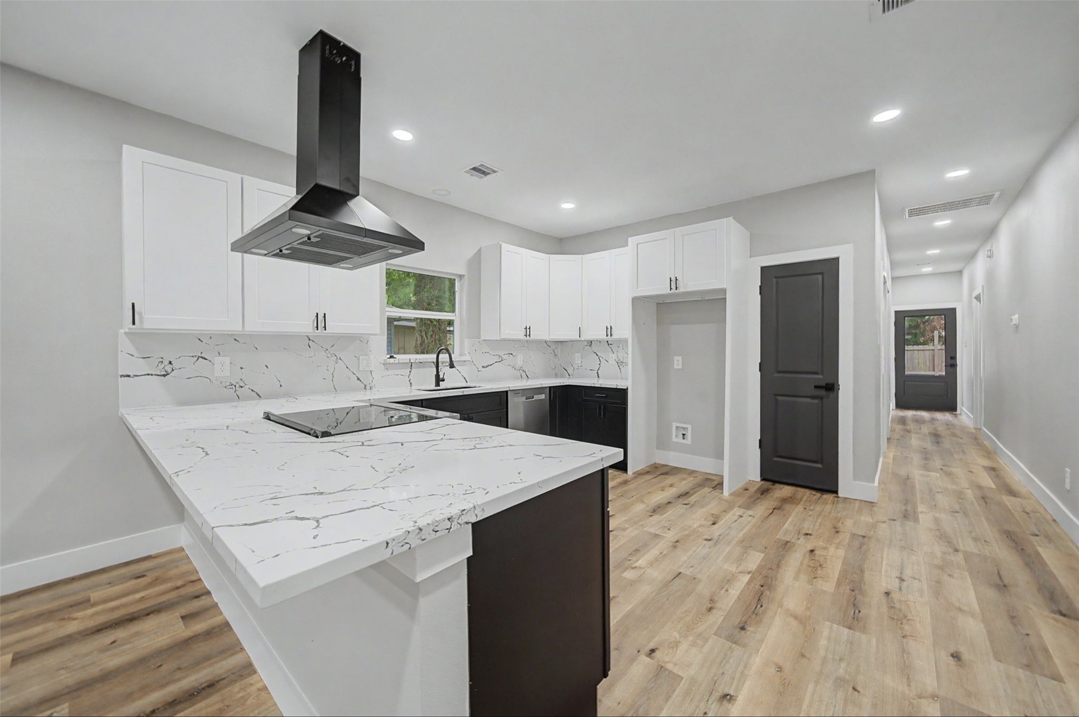 2338 Lidstone Street Houston, TX 77023 - Photo 12 of 17 Modern kitchen features sleek white cabinetry, quartz countertops with an integrated cooktop.