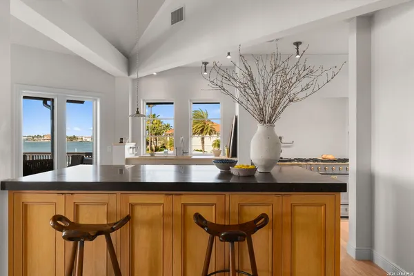 a living room with stainless steel appliances granite countertop furniture wooden floor and a kitchen view