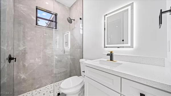 a bathroom with a sink a toilet a shower and a mirror