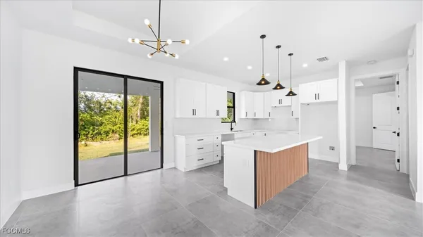 a large white kitchen with a large window a sink and stainless steel appliances