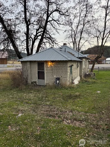 a backyard of a house with plants and large tree