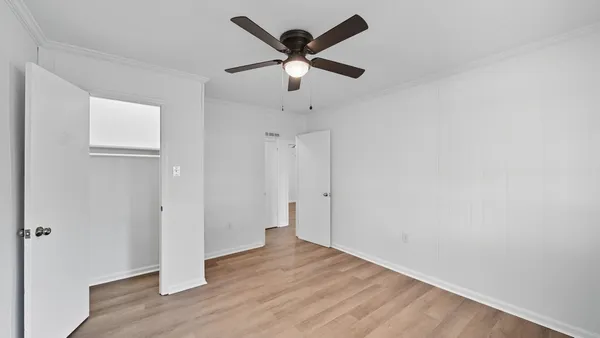 an empty room with wooden floor and ceiling fan