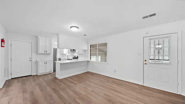 a large white kitchen with white cabinets and wooden floor