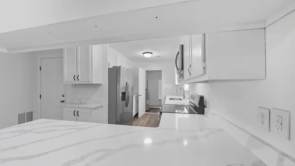 a large white kitchen with granite countertop a sink