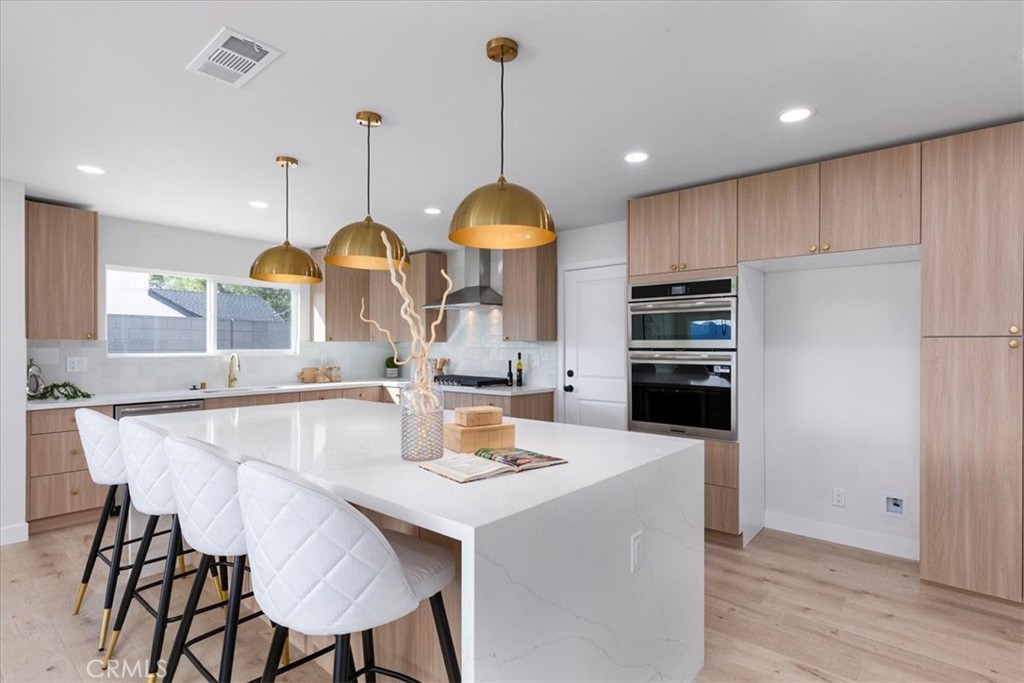 26002 Adamor Road Calabasas, CA 91302 - Photo 9 of 39 a kitchen with stainless steel appliances granite countertop a sink a stove a refrigerator and a dining table with wooden floor