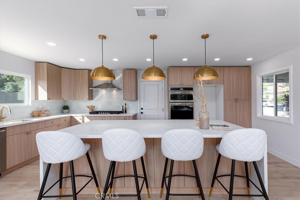 26002 Adamor Road Calabasas, CA 91302 - Photo 10 of 39 a kitchen with stainless steel appliances a dining table chairs and wooden cabinets