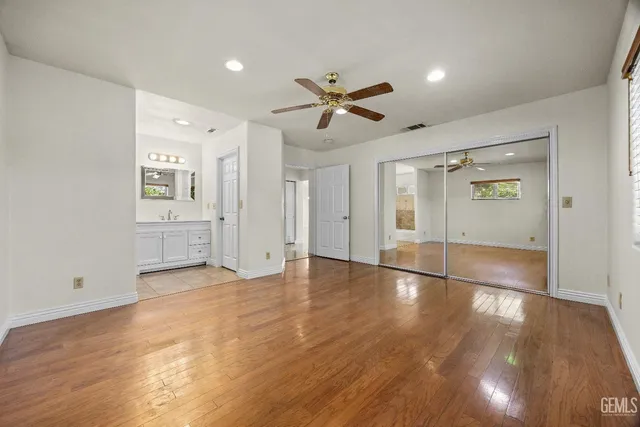 a view of empty room with wooden floor and fan