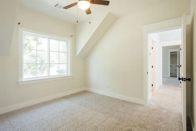 an empty room with a chandelier fan and windows