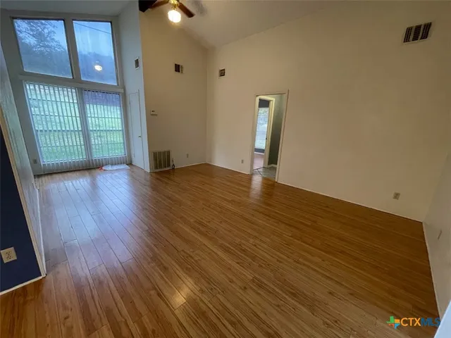 a view of an empty room with wooden floor and a window