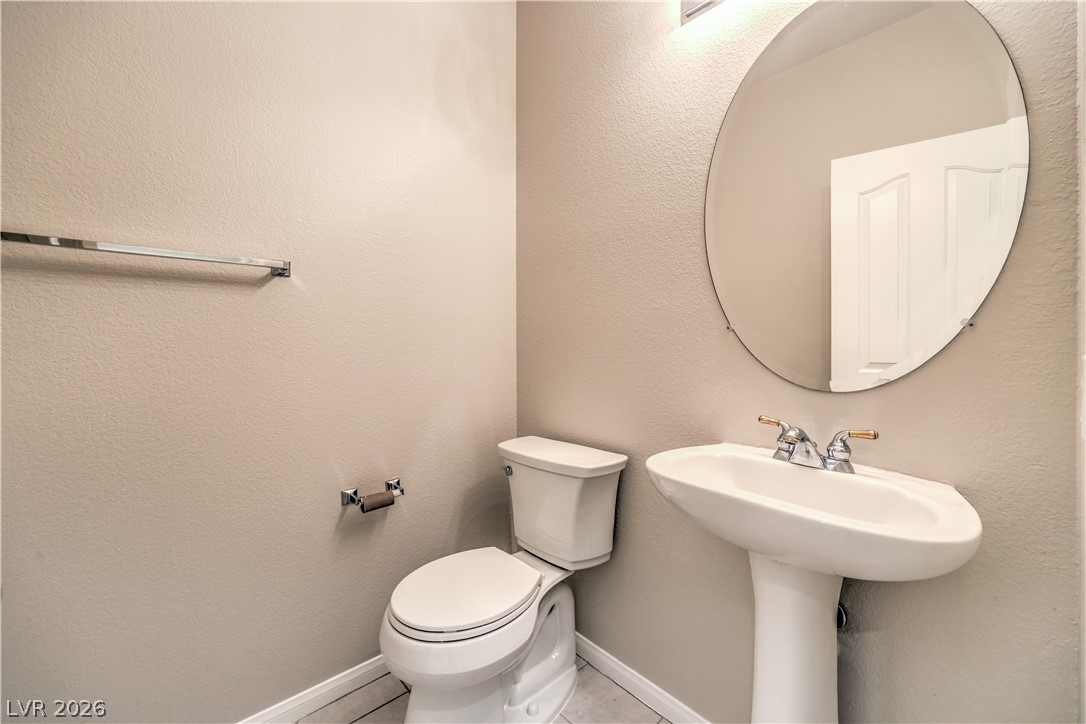 3713 Spring Shadow Road Las Vegas, NV 89129 - Photo 19 of 37 This convenient half-bath features a contemporary pedestal sink and a sleek oval mirror, enhancing its modern simplicity.