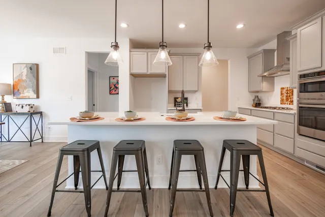 a kitchen with stainless steel appliances granite countertop a table chairs stove and wooden floor