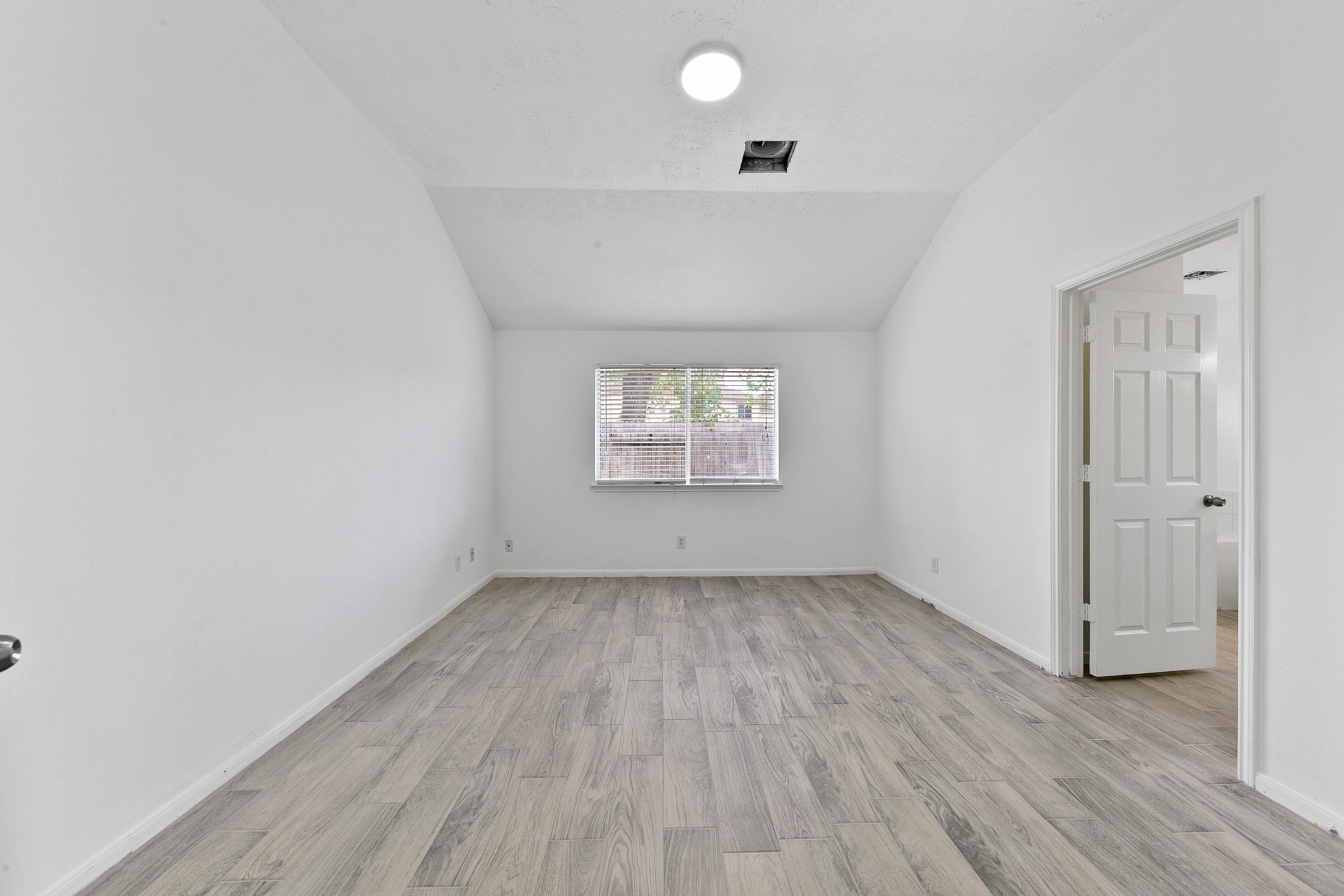 12014 Raven View Drive Houston, TX 77067 - Photo 22 of 29 This room features a vaulted ceiling, wood-look flooring, and a window providing natural light. It has a neutral color scheme and an open doorway leading to an adjacent space.