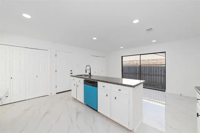 a kitchen with stainless steel appliances granite countertop a sink and dishwasher with white cabinets