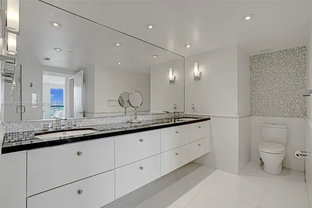 a bathroom with a granite countertop sink a toilet and a mirror