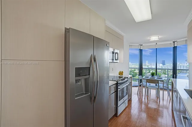 a kitchen with granite countertop a refrigerator a stove a dining table and chairs with wooden floor