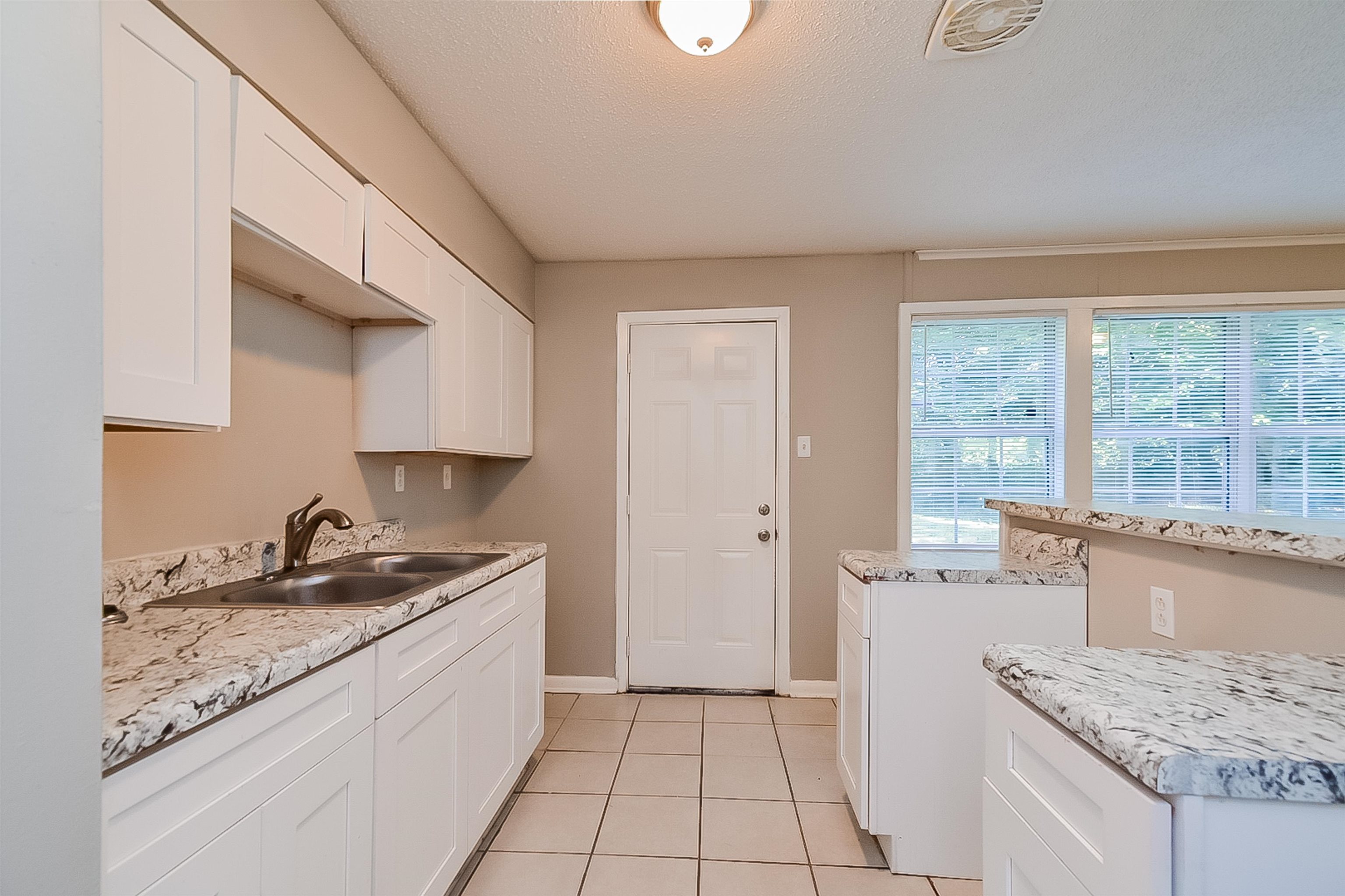 3020 Capri Road Memphis, TN 38118 - Photo 13 of 14 Kitchen featuring white cabinetry, light tile patterned floors, a textured ceiling, and light stone countertops