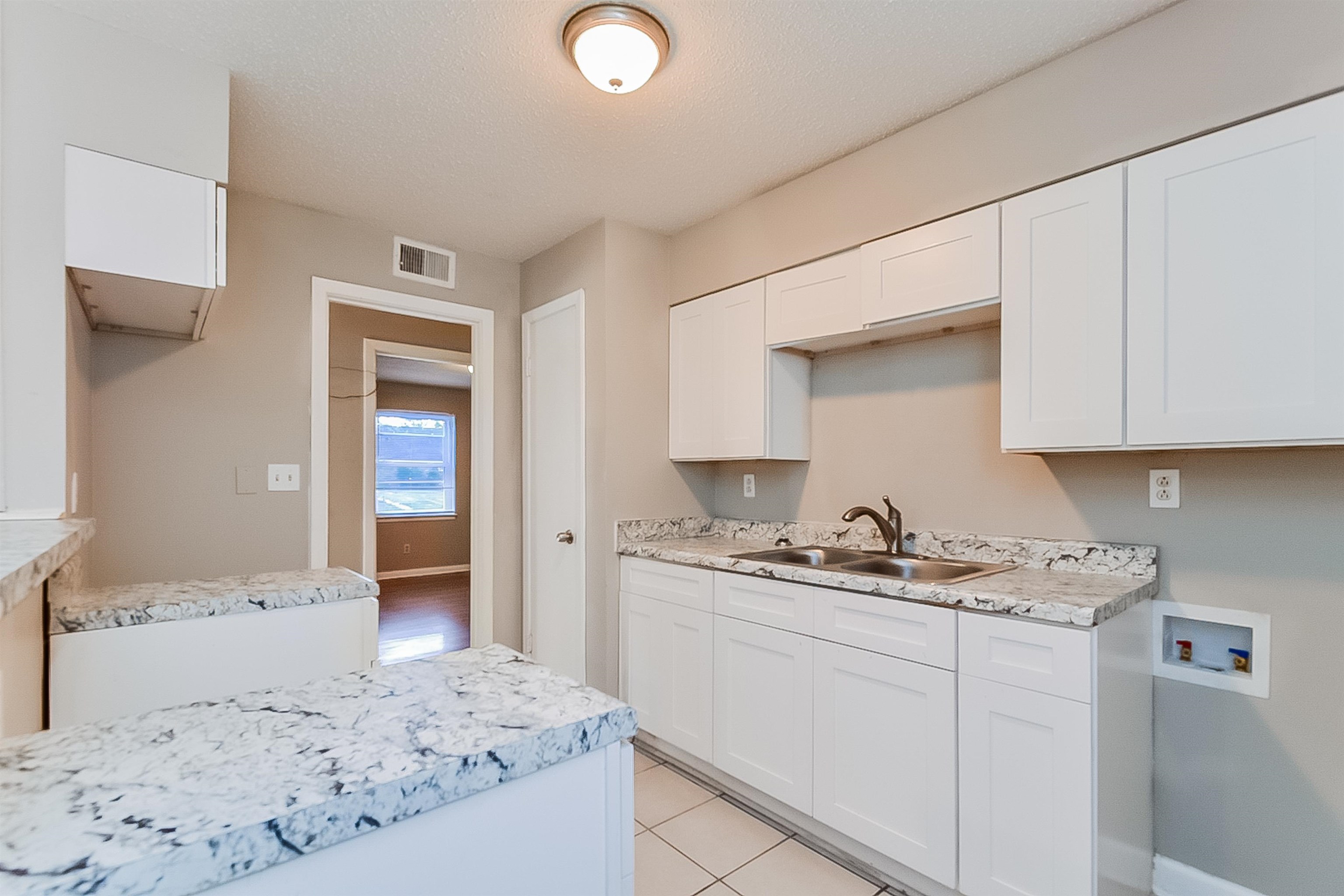 3020 Capri Road Memphis, TN 38118 - Photo 2 of 14 Kitchen with light countertops, white cabinetry, light tile patterned floors, and a textured ceiling