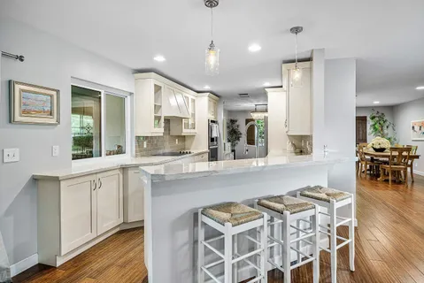a kitchen with stainless steel appliances granite countertop a stove a sink dishwasher and a dining table with wooden floor