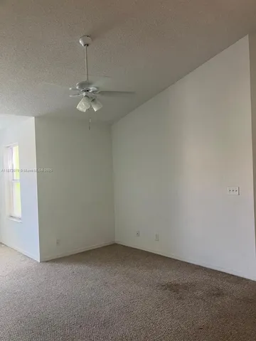 an empty room with windows and chandelier fan