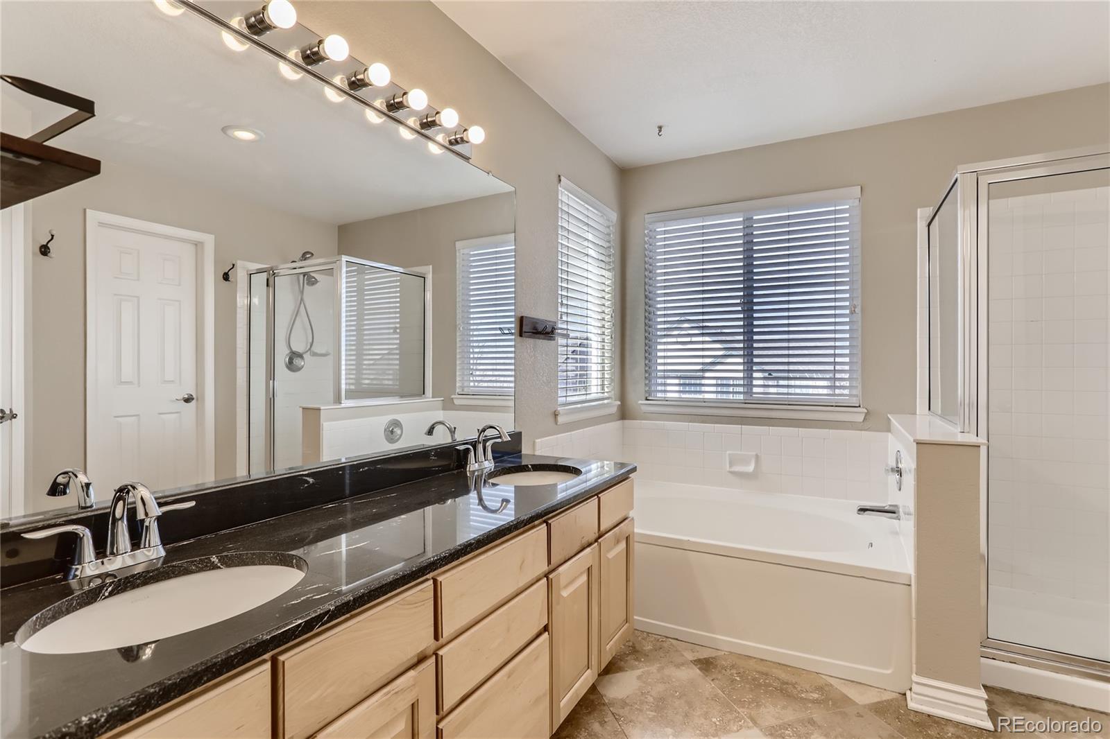 3905 South Kirk Way Aurora, CO 80013 - Photo 17 of 33 a bathroom with a granite countertop sink mirror and a bathtub