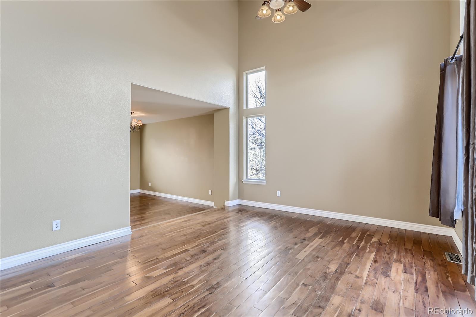 3905 South Kirk Way Aurora, CO 80013 - Photo 4 of 33 a view of an empty room with wooden floor and a window