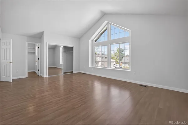 an empty room with wooden floor and windows
