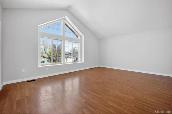 an empty room with wooden floor and windows