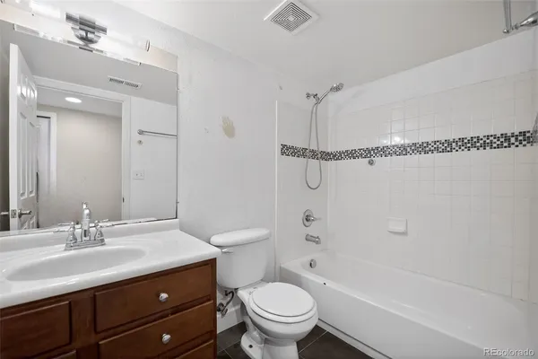 a bathroom with a granite countertop sink a toilet and shower
