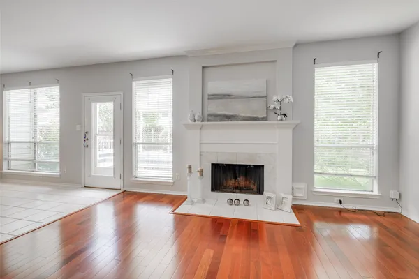 an empty room with fireplace wooden floor and windows