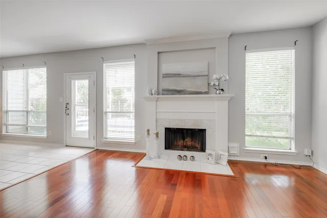 an empty room with fireplace wooden floor and windows