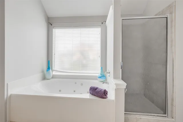 a bathroom with a bathtub a shower and a window