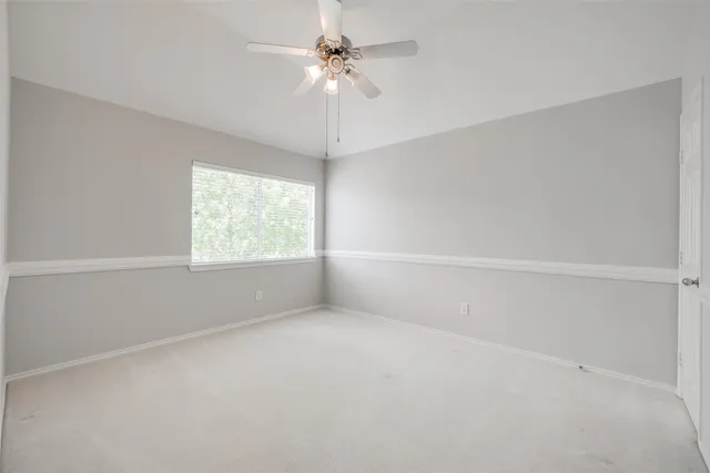 an empty room with a window and a ceiling fan