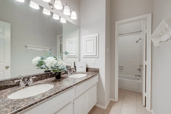 a bathroom with a granite countertop double vanity sink and a mirror