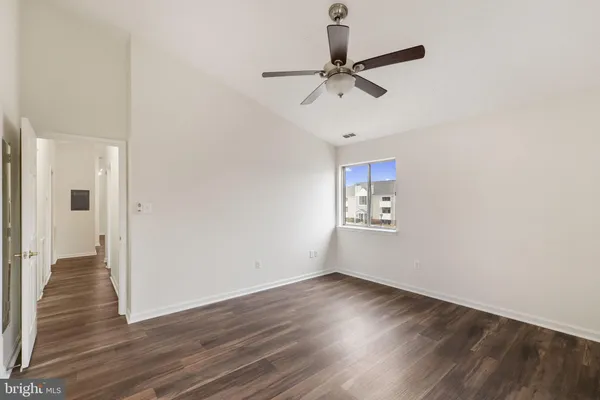 a view of empty room with wooden floor and fan