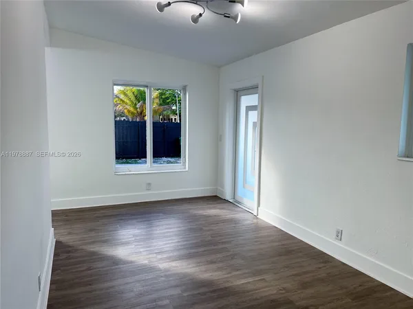 an empty room with wooden floor cabinet and windows