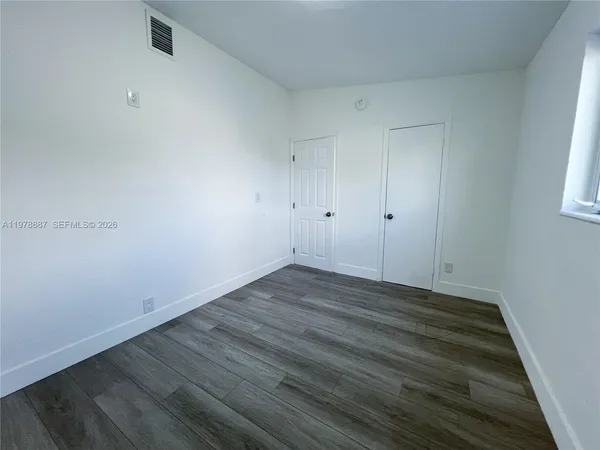 a view of an empty room with wooden floor