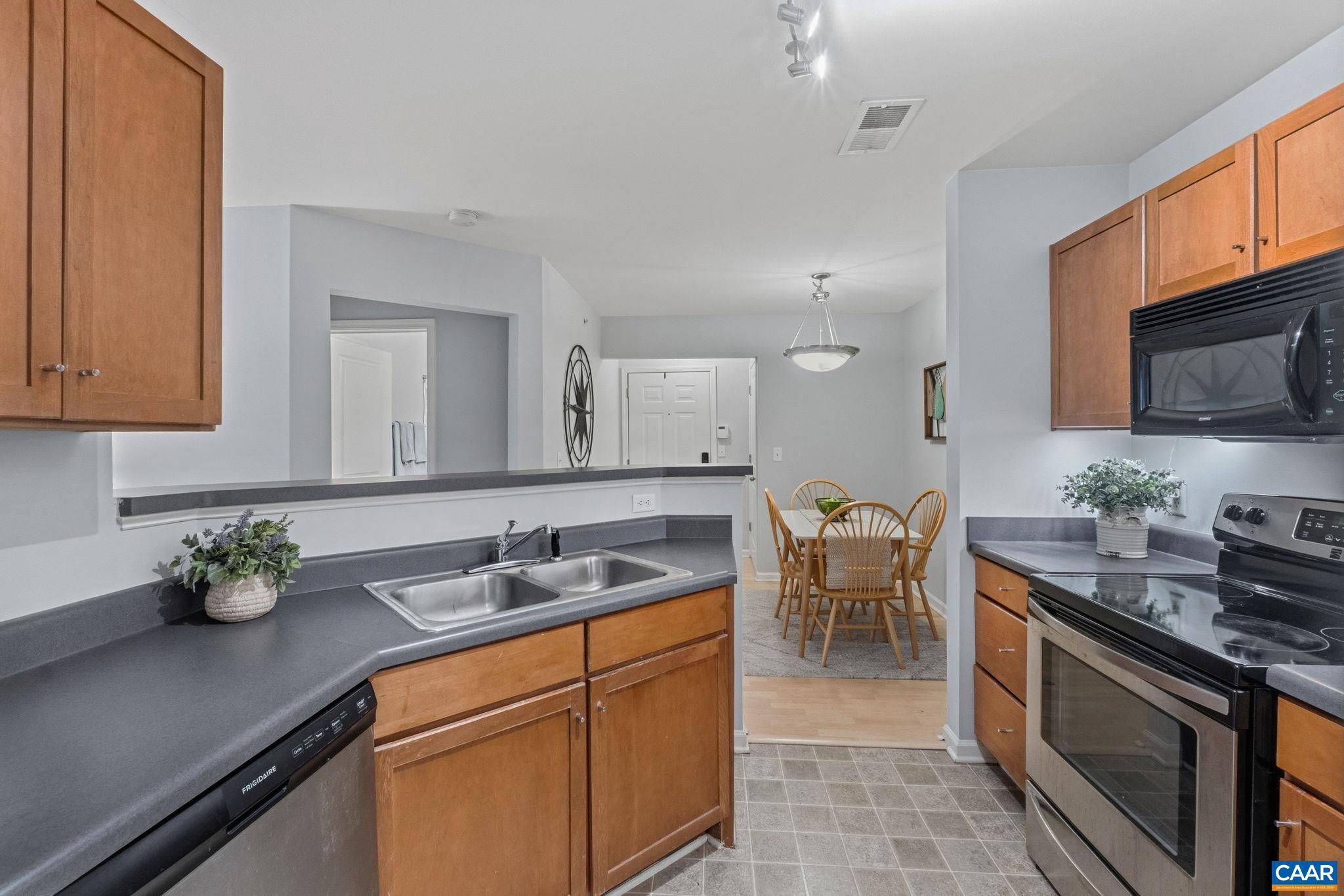720 Walker Square, Unit 1B Charlottesville, VA 22903 - Photo 9 of 29 a kitchen with stainless steel appliances granite countertop a sink a stove top oven a dining table and chairs