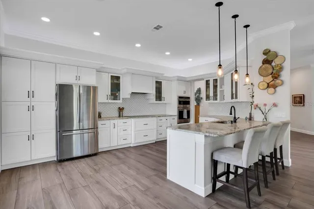 a kitchen with stainless steel appliances granite countertop a dining table chairs stove refrigerator and cabinets