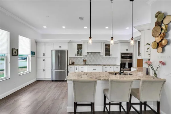 a kitchen with stainless steel appliances granite countertop a sink a stove a refrigerator and island with wooden floor