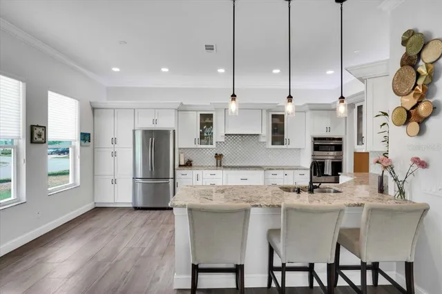 a kitchen with stainless steel appliances granite countertop a sink a stove a refrigerator and island with wooden floor