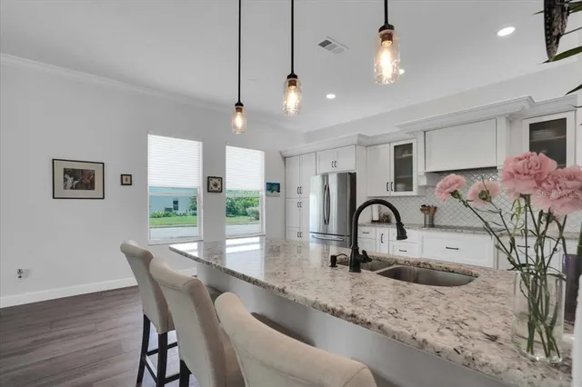 a kitchen with stainless steel appliances granite countertop a table chairs in it and wooden floors