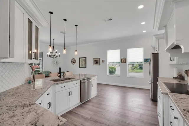a kitchen with stainless steel appliances granite countertop a sink a stove and a wooden floors