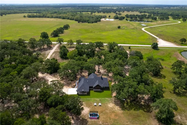 an aerial view of ocean with residential house with outdoor space and trees