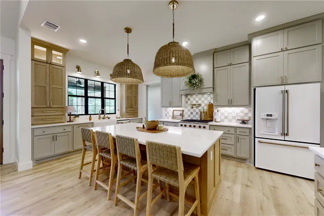 a kitchen with stainless steel appliances granite countertop a dining table chairs refrigerator and cabinets