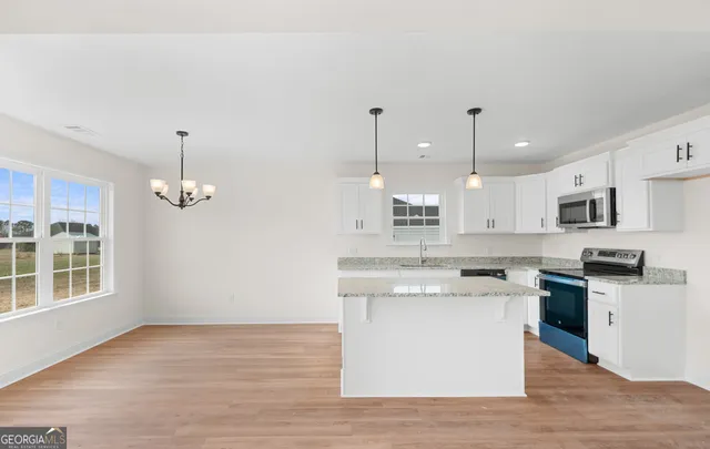 a kitchen with stainless steel appliances granite countertop a stove a sink dishwasher and a oven with wooden floor