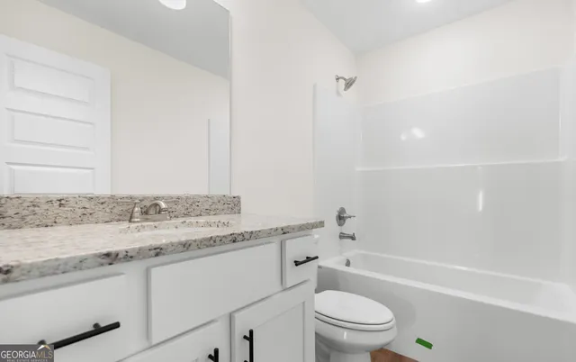 a bathroom with a granite countertop sink a toilet and bathtub