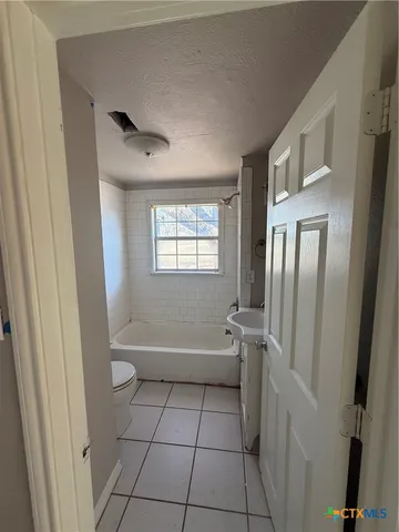 a bathroom with a granite countertop bathtub shower and toilet