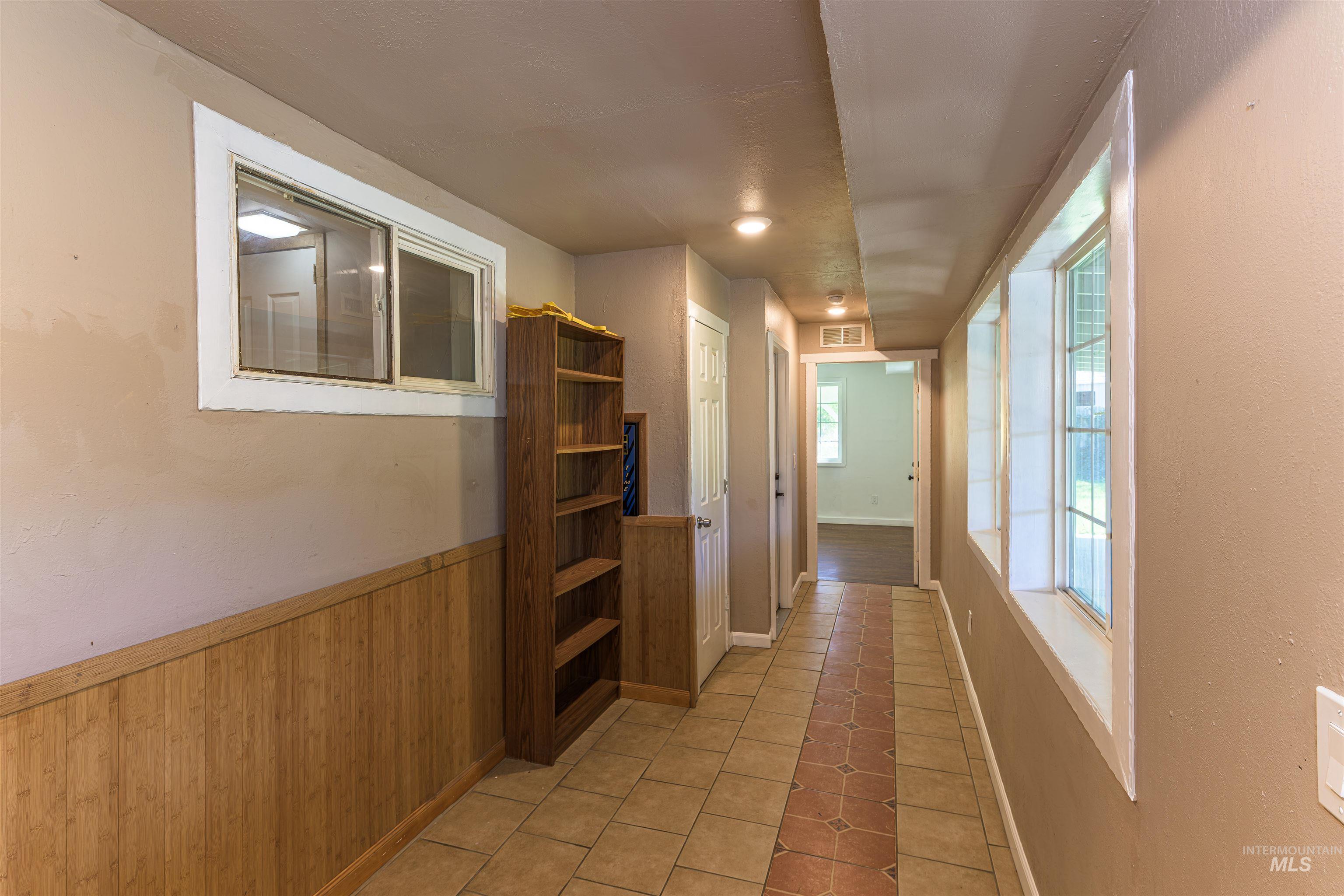 2003 North Cole Road Boise, ID 83704 - Photo 14 of 40 Hall featuring light tile patterned floors, wooden walls, and wainscoting