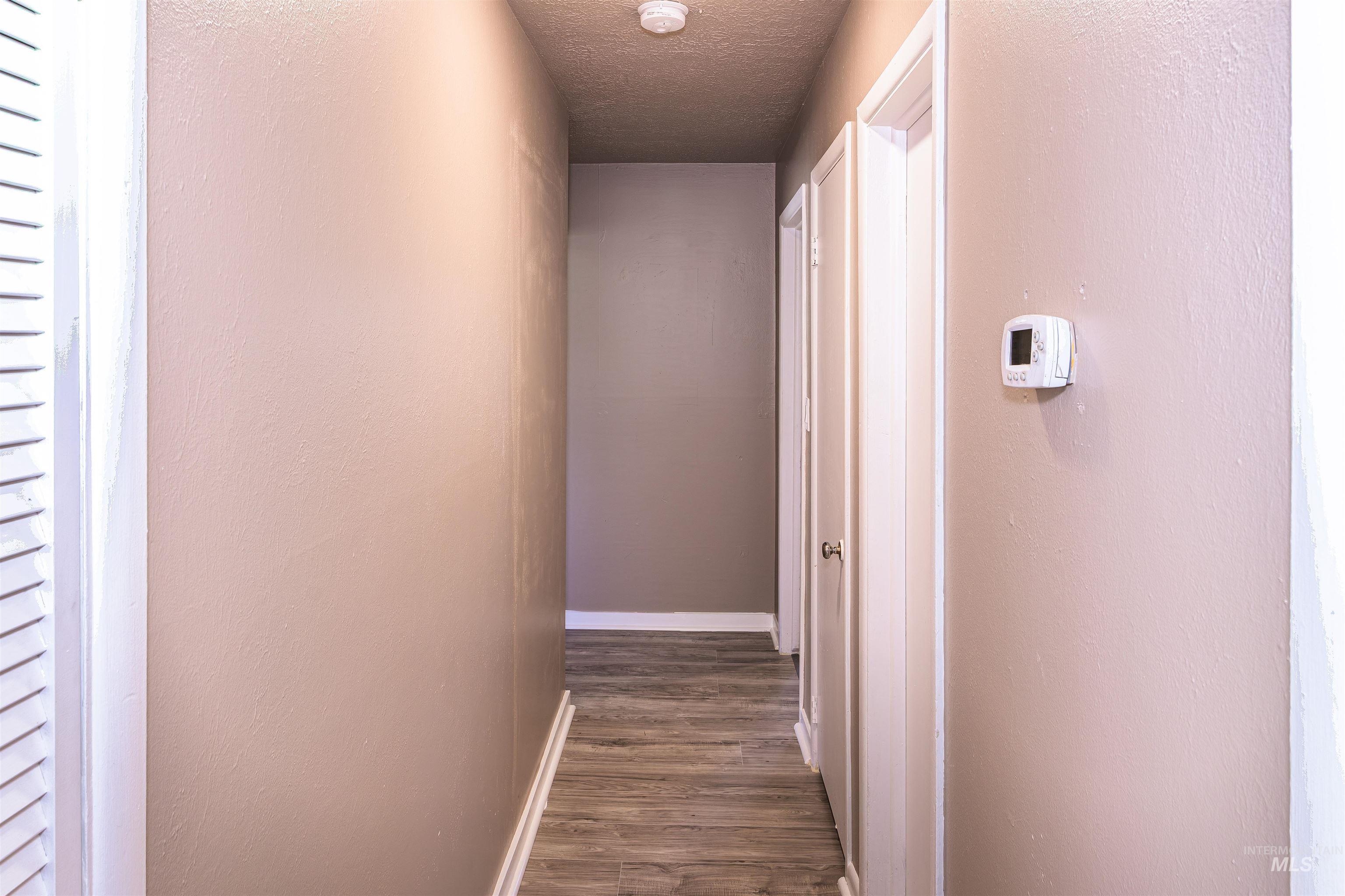 2003 North Cole Road Boise, ID 83704 - Photo 20 of 40 Hall featuring a textured ceiling, dark wood-type flooring, and a textured wall